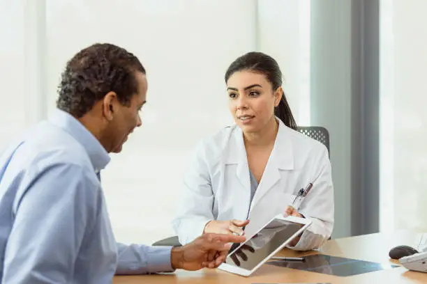 Photo of Doctor and patient discuss test results on digital tablet