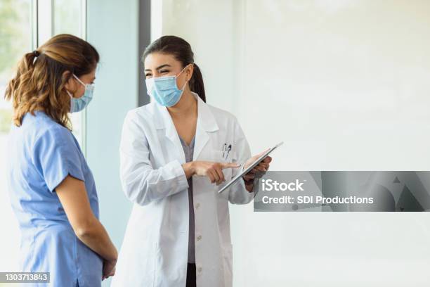 Smiling Female Doctor Points To Patients Test Results On Tablet Stock Photo - Download Image Now