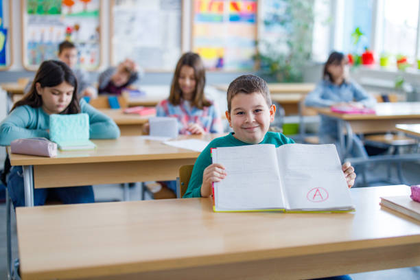 Happy schoolboy showing his A grade on a test at elementary school Happy schoolboy showing his A grade on a test at elementary school report card stock pictures, royalty-free photos & images