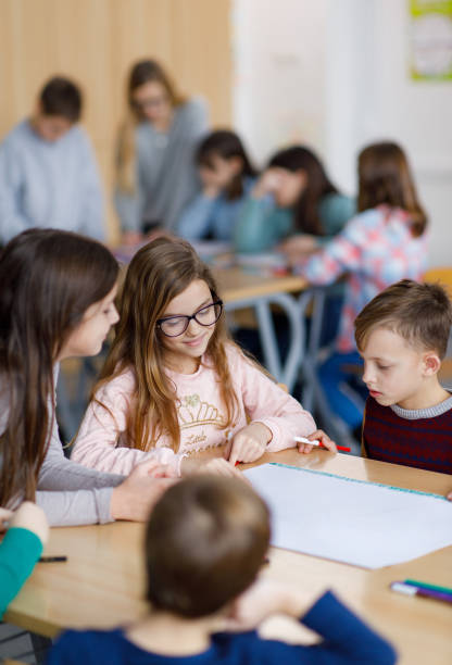 Group of happy elementary students drawing in the classroom stock photo