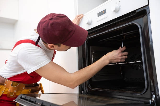 istock handsome young repairman fixing oven with screwdriver 1303715532