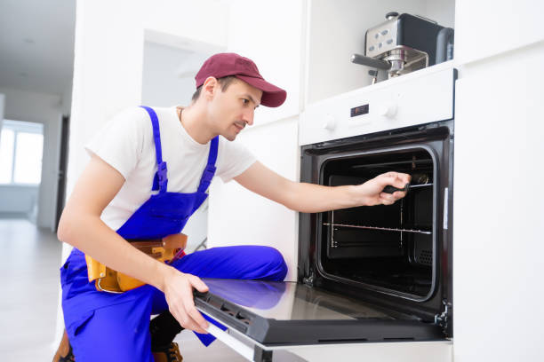 istock handsome young repairman fixing oven with screwdriver 1303716577