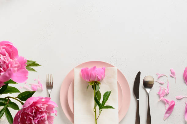 istock Spring table setting with pink peony flowers on a white table. View from above. 1303716936