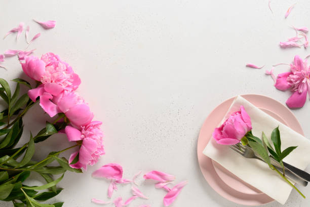 istock Spring table setting with pink peony flowers on a white table. View from above. 1303716939