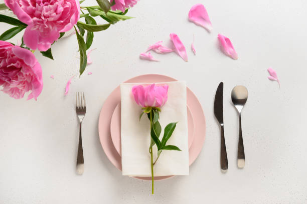 istock Spring table setting with pink peony flowers on a white table. View from above. 1303716940