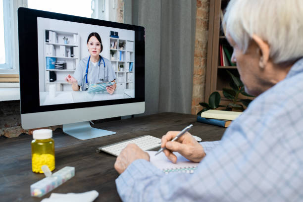 istock Sick senior man writing down advice of doctor while sitting in front of computer 1303718057