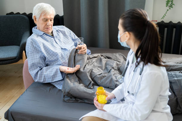 istock Sick elderly man in pajamas going to take new effective pills against covid 1303718082