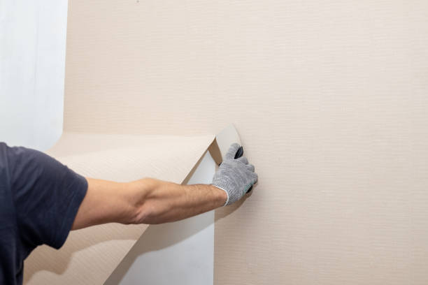 Man hand tear off old light wallpaper from wall.Preparing for home repair work.removing Wallpaper with a spatula, the process of updating the wall room repair. copy space