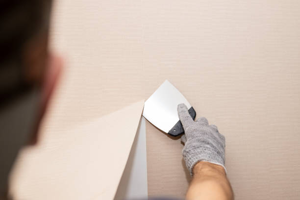 istock Man hand tear off old light wallpaper from wall.Preparing for home repair work.removing Wallpaper with a spatula, the process of updating the wall room repair. copy space 1303719287