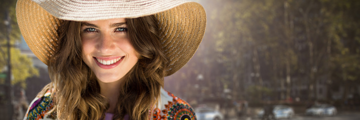 Beautiful woman with a straw hat  against picture of a city