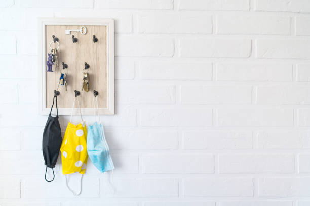 istock Tree protective face masks on the keys organizer hook on the loft design white background brick wall in the home hallway. Health care concept during COVID-19 pandemic concept background image. 1303722926