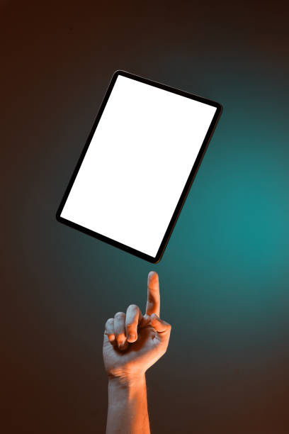Male hand hold on finger levitating modern tablet mockup with empty screen for content and advertising on green backdrop. High quality photo