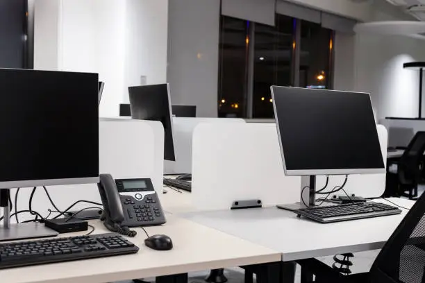 Photo of Empty modern office with computers and phone at night