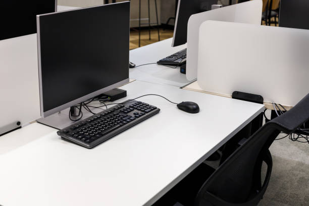 istock Computer monitor on an empty desk in a modern office with black keyboard and wired mouse 1303724247