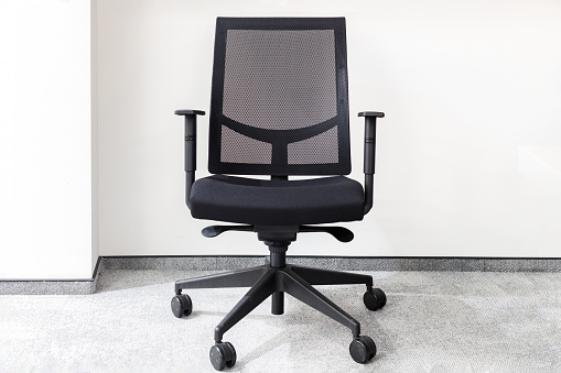 Moderna silla de oficina negra en una oficina vacía contra la pared blanca en la alfombra gris photo