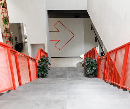 Red staircase in a modern office with a large arrow, derection concept, business background