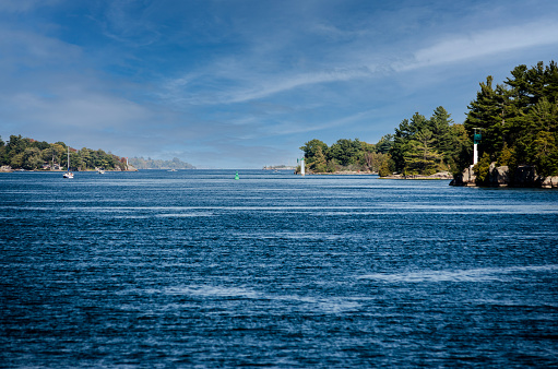 Vanishing point view of islands and light beacons in the St. Lawrence River under a wispy blue sky