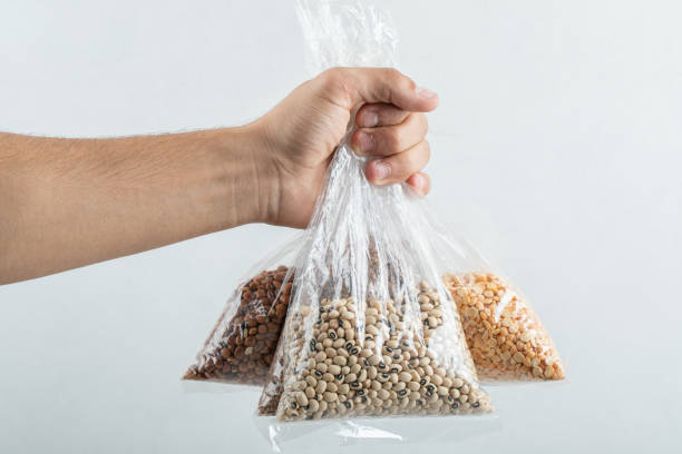 istock Man hand holding bags with raw beans on a white background 1303727379