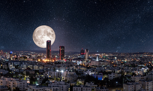 Full moon behind modern buildings in the new downtown of Amman city