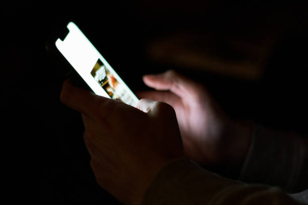 istock Hands holding a turned on phone in the dark 1303728366