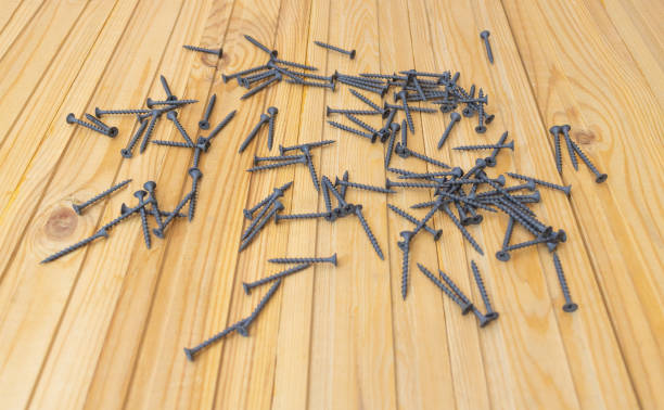 istock Black Screws on wooden background. Hardware for construction 1303729521
