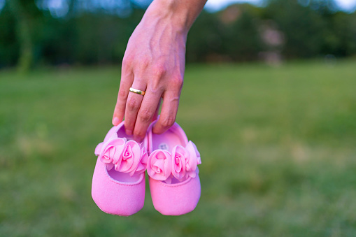 Woman holding a pair of pink baby shoes outdoors