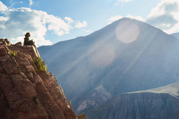 Man meditating with mountain, sun and sky stock photo