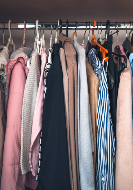 Things on hangers hang in a row. Storage of things Things on hangers hang in a row. Storage of things. Side view, vertical. colorful check shirts on sale at a clothing store stock pictures, royalty-free photos & images