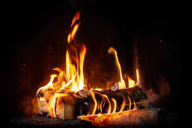 log fire and firewood in the fireplace for a cozy winter atmosphere stock photo