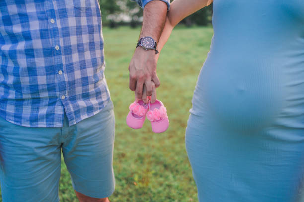 zukünftige eltern halten hände und ein paar kleine schuhe - pair couple mid adult happiness stock-fotos und bilder