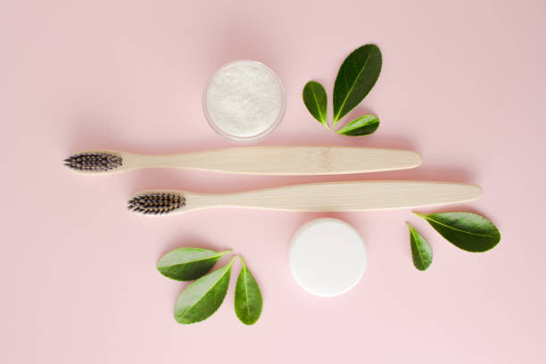 istock Eco-friendly bamboo toothbrushes, dentifrice and green leaf on pink background. 1303735600