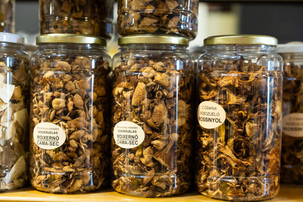 Dried mushrooms in jars in grocery Dried red and black chanterelles, champignons, fairy-ring mushrooms in jars at grocery store counter marasmius oreades mushrooms stock pictures, royalty-free photos & images