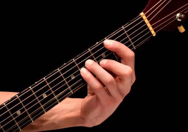 On a black background the playing guitarist chords on strings