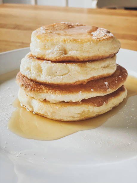 Stack of homemade Japanese souffle pancakes with syrup and icing sugar