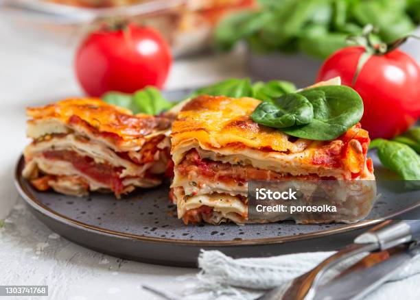 Italian Lasagna With Tomato Sauce And Cheese Served With Tomatoes And Spinach Light Concrete Background Homemade Vegetarian Lasagna Stock Photo - Download Image Now