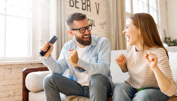 istock Happy couple celebrating victory while watching TV 1303744219