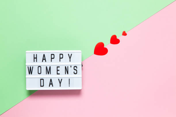 istock Light board with inscription Happy Women's Day, three red different-sized hearts on pastel background pink and green, copy space. Horizontal. International 8 March Day festive concept 1303744492