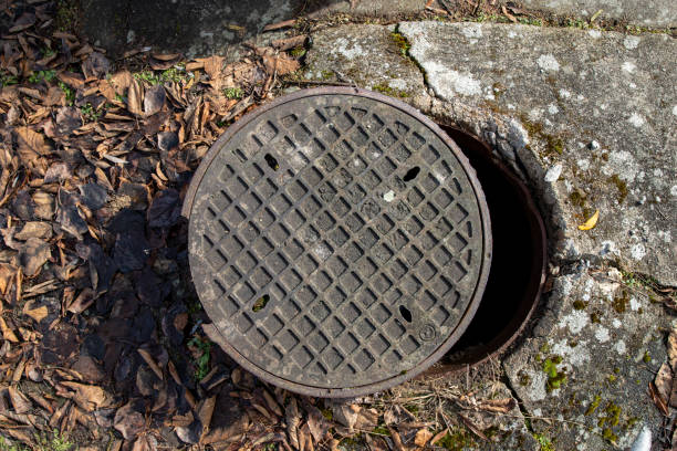 Open cast iron cover of the sewage chamber. Dangerous glitch for pedestrians on a sidewalk in the city. Spring season. Open cast iron cover of the sewage chamber. Dangerous glitch for pedestrians on a sidewalk in the city. Spring season. sewer lid stock pictures, royalty-free photos & images