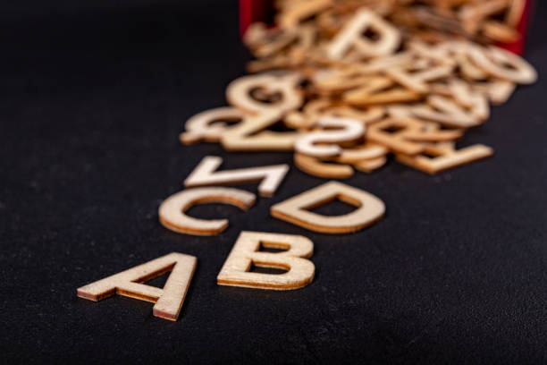 istock A stack of small wooden letters on a dark table. Letters outlines for arranging inscriptions and words. Dark background. 1303744647