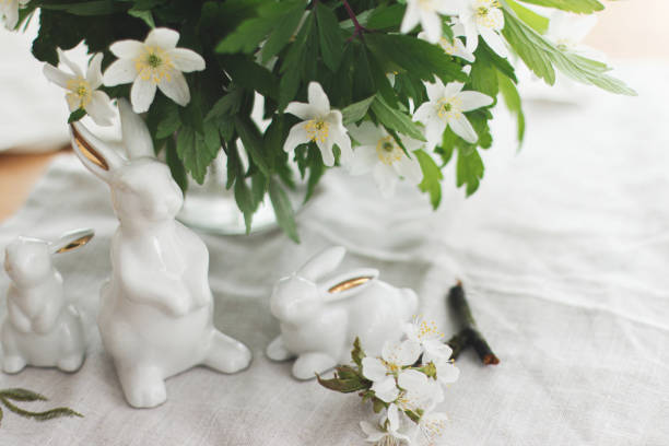 istock Cute white bunnies and spring flowers on linen cloth  on rustic table in soft light. Happy Easter 1303745605