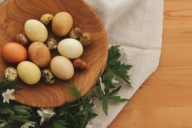 istock Modern easter eggs in wooden bowl with spring flowers on rustic table, top view. Happy Easter! 1303745652
