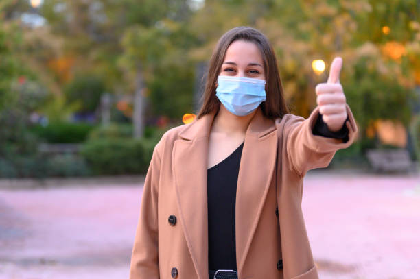 istock Woman gesturing approval by wearing a protective mask 1303745805