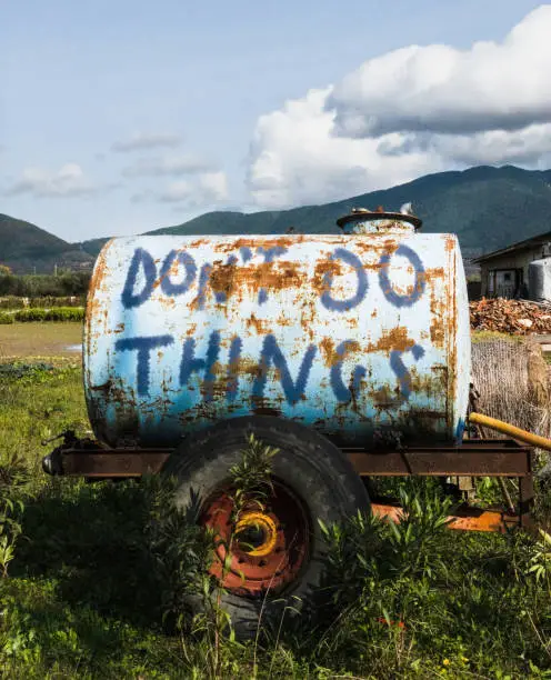 In praise of laziness: "Don't do things" is written on an old, rusty portable water tank. *** The text was digitally superimposed and a release is provided ***