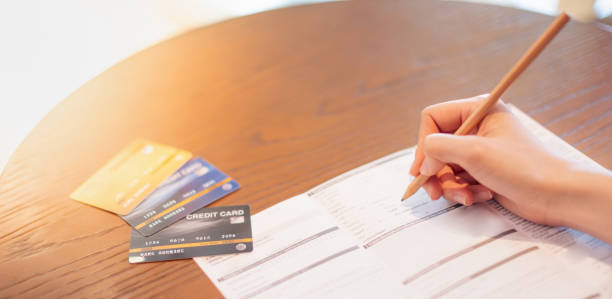 The female hand writing on the Blank credit application form  for applying the credit card on table wood. stock photo