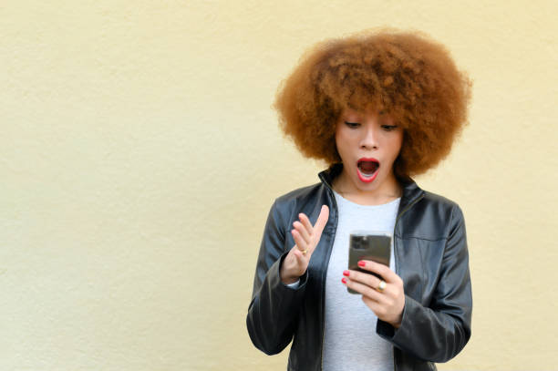 istock open-mouthed woman looking at her phone 1303748964