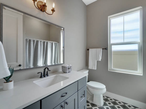 istock Modern Guest Bathroom with White Countertops and Grey Cabinets with Grey and White Patterned Tile Floors 1303750006