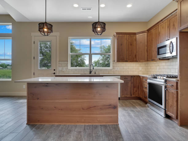 Modern New Kitchen Light and Bright kitchen Real Estate Listing with Brown Red Cabinets and Grey Hard Wood Floors Straight On View stock photo