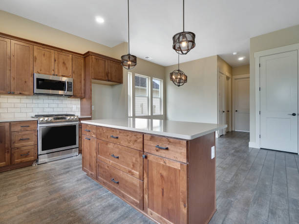 istock Modern New Kitchen Light and Bright kitchen Real Estate Listing with Brown Red Cabinets and Grey Hard Wood Floors Back of Kitchen Island View 1303750066