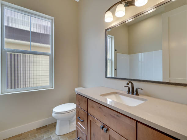 Modern Guest Bathroom with Light Brick Flooring and Brown Cabinets and Off White Countertops Guest bathroom with off white countertops and light brick flooring, white sink, black faucet vanity mirror stock pictures, royalty-free photos & images