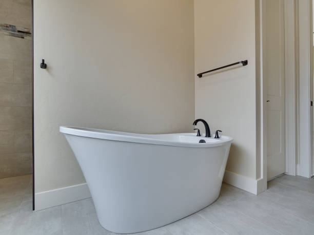 Modern Master Bathroom Freestanding Bathtub with Black Hardware and Beige Walls stock photo